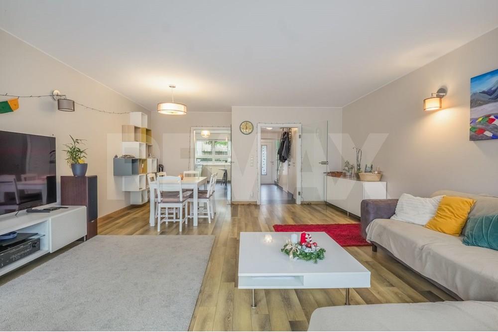 Dining area with a white table and chairs beside open shelving, looking toward the living room and hallway.