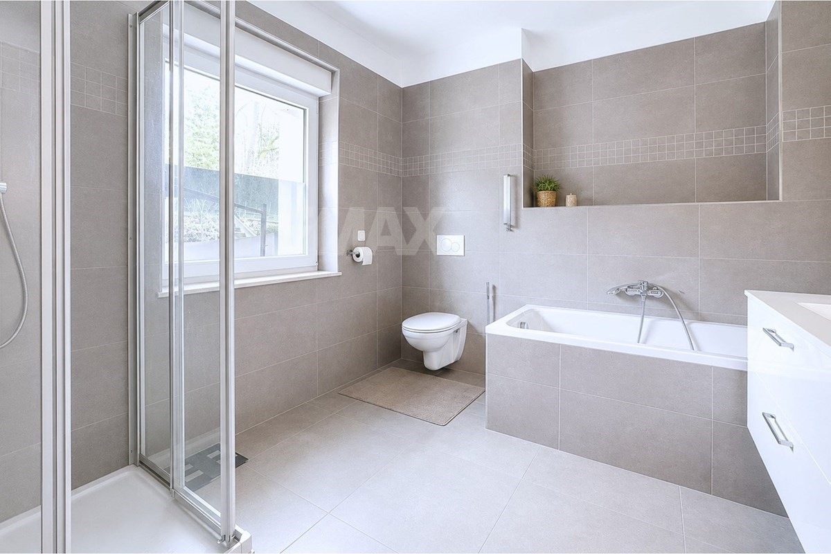 Tiled bathroom with a glass walk-in shower, built-in bathtub, wall-hung toilet, large mirror, recessed shelf, and two windows.