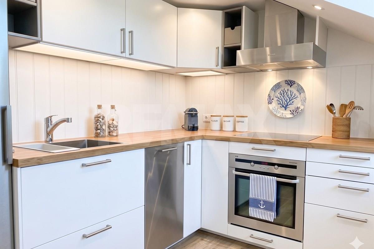 White L-shaped fitted kitchen with wood-effect counters, integrated appliances, sink, under-cabinet lighting, and labeled storage jars.